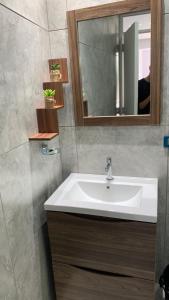 y baño con lavabo blanco y espejo. en MILANO SUITE, en San Ramón
