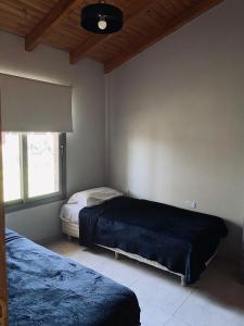 1 dormitorio con 2 camas y ventana en Cabañas Golden en San Rafael