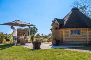 een man onder een paraplu naast een hut bij Chalets Clos du marais in Chemillé