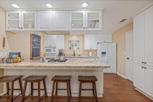 eine Küche mit weißen Schränken und Barhockern in der Unterkunft Yosemite Bass Lake Adventure Oasis in Bass Lake