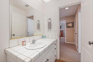 ein weißes Badezimmer mit Waschbecken und Spiegel in der Unterkunft Yosemite Bass Lake Adventure Oasis in Bass Lake + 33 Fotos