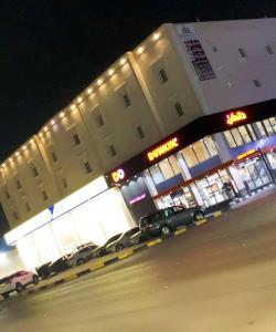 un edificio con coches aparcados delante de él por la noche en شقة خاصة مؤثثة بالكامل للتأجير اليومي, en Hafr Al Batin
