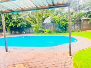 a swimming pool in a yard with a pergola at OGL Guesthouse in Vanderbijlpark