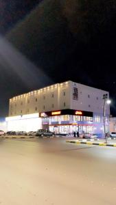 ein großes weißes Gebäude mit einem Parkplatz in der Nacht in der Unterkunft شقة خاصة مؤثثة بالكامل للتأجير اليومي in Hafar Al-Batin