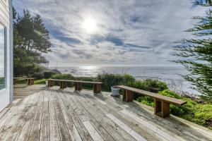 una terraza de madera con bancos y vistas al océano en Harbor House, en Brookings