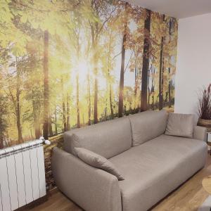 a couch in a living room with a forest mural at Duki1 in Novi Beograd