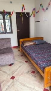 um quarto com uma cama, uma cadeira e decorações em KS Home Stay em Tiruchchendūr