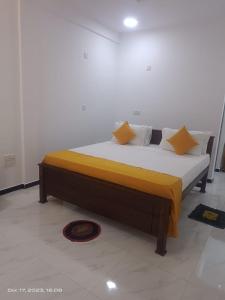 Dream Guest House في ترينكومالي: سرير في غرفة مع أغطية ومخدات صفراء