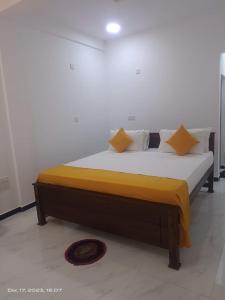 a large bed in a room with yellow sheets and pillows at Dream Guest House in Trincomalee