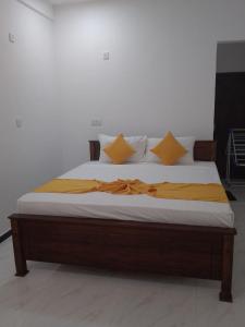 Una cama con sábanas amarillas y almohadas. en Dream Guest House, en Trincomalee