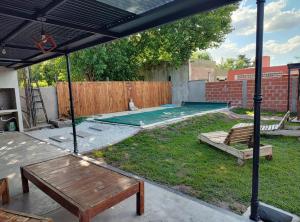un patio trasero con una piscina con mesa y bancos en Los Abuelos en Duggan