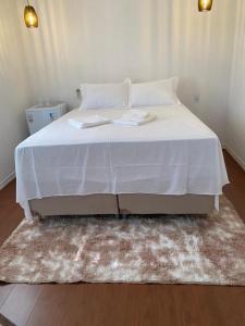 a bed with a white blanket and a rug at Bangalô Miraflores in Chapada dos Guimarães