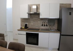 a kitchen with white cabinets and a sink and a refrigerator at La casa dei nonni in San Giuseppe Vesuviano