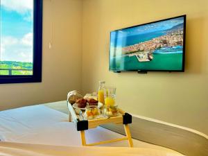 a room with a tv and a tray of food on a bed at Villa Cristalle - Campos do Jordão in Campos do Jordão