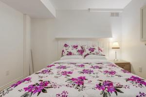 a bedroom with a bed with purple flowers on it at Comfortable Whitby 2 Bedroom Lower Suite in Whitby