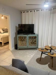 a living room with a flat screen tv on a stand at Harbor View, short 7 minute walk to beach. in Vero Beach