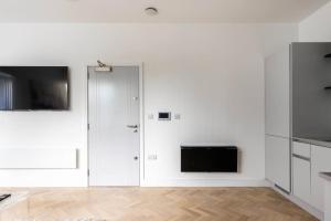 een witte keuken met witte kasten en een televisie bij Gorgeous, Modern apartment-fantastic location in Slough