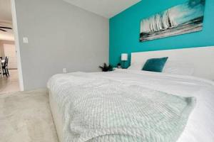 a bedroom with a white bed with a blue wall at Charming Beach Condo located in Amazing Location! in St Pete Beach