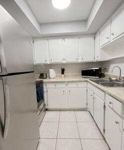 a white kitchen with white cabinets and a refrigerator at Charming Beach Condo located in Amazing Location! in St. Pete Beach