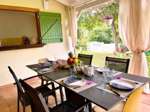 une table à manger avec des chaises et une table avec des assiettes et des verres dans l'établissement Villa L'Orangeraie, à Le Moule