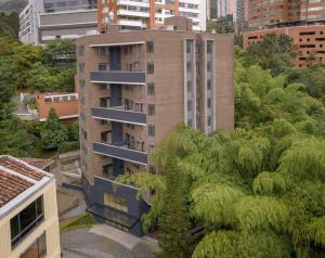 a tall building with trees in front of it at El Tesoro Medellín Hab311 by Letoh in Medellín