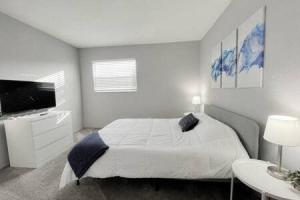 a white bedroom with a bed and a tv at 2 Bedroom Beach Condo With Dock AND Walk To Everything in St Pete Beach