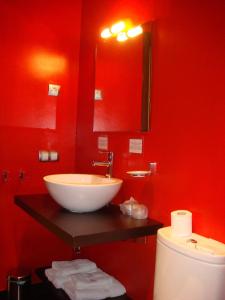 een badkamer met een wastafel en een rode muur bij Hotel León Tierra de Vinos in La Palma del Condado