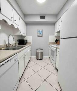 a kitchen with white cabinets and a refrigerator at 2x1 Beach Condo! Walk to the Beach AND Restaurants! in St Pete Beach