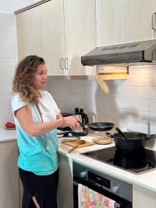 a woman standing in a kitchen preparing food at Teleport Coliving Cyprus in Pano Lefkara
