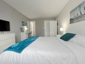 a bedroom with a large white bed and a flat screen tv at Beautiful 2 Bed Beach Condo With DOCK - Walk Everywhere! in St Pete Beach