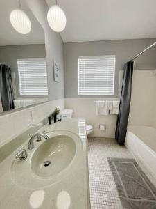 a bathroom with a sink and a mirror and a tub at Beautiful 2 Bed Beach Condo With DOCK - Walk Everywhere! in St. Pete Beach