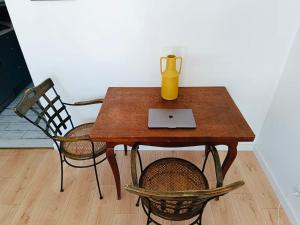 a wooden table with a laptop and two chairs at Gîte Mas Provençal Piscine Parking Privé L'Isle-Sur-La-Sorgue in LʼIsle-sur-la-Sorgue