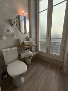 La salle de bains est pourvue de toilettes, d'un lavabo et d'un miroir. dans l'établissement Hôtel Amaryllis, à Nice