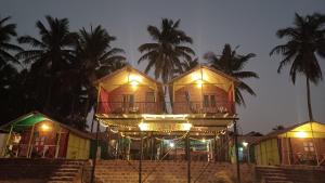 a building with lights on it with palm trees at Nana's Nook in Agonda