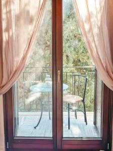 uma porta de vidro com uma mesa e uma cadeira numa varanda em Filimon GuestHouse Villa em Xanthi