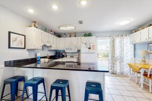 a kitchen with white cabinets and blue stools at Healing Hideaway in Saint Joe Beach