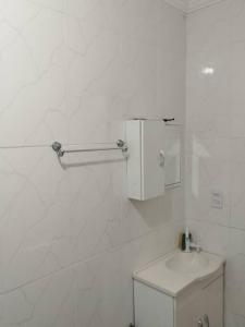 a white bathroom with a toilet and a sink at Canto do Forte Apto térreo in Praia Grande