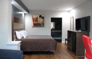 a hotel room with a bed and a flat screen tv at Grand Villa Inn and Suites Westchase/Chinatown in Houston