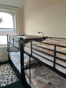 three bunk beds in a room with a window at Botanic Avenue Hostel less than a mile from the City Centre in Belfast