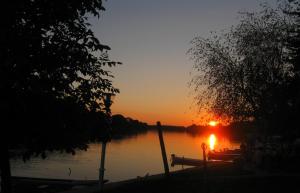 una puesta de sol en un lago con un barco en el agua en Relax House Irina, en Novi Bečej