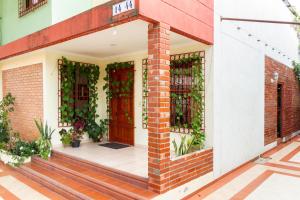a brick building with a red door and plants at Hostal Cartagonova - Habitaciones privadas y amplias cerca a zonas turísticas in Cartagena de Indias