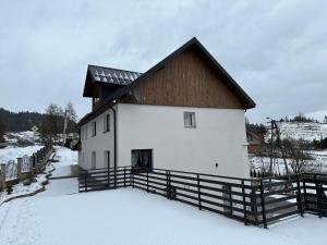 un edificio bianco con tetto marrone nella neve di Pod Skałką a Sromowce Wyżne