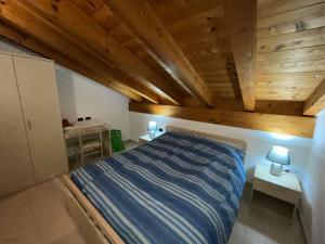 1 dormitorio con cama y techo de madera en L'Acero Rosso, en Prosto di Piuro