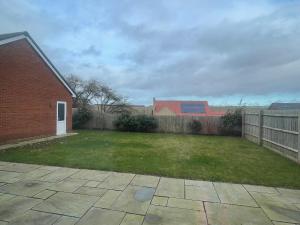 a yard with a brick building and a fence at 3 swallow close IDEAL FOR CONTRACTORS , FAMILIES AND WEEKEND STAYS in Olney
