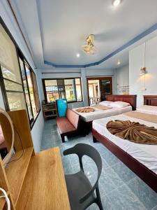 ハード・ヤオにあるユーフォリア バンガローのベッド3台、テーブル、椅子が備わる客室です。
