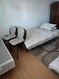 ein Bett und zwei Stühle in einem Zimmer in der Unterkunft Topli kutak Banja Luka in Banja Luka