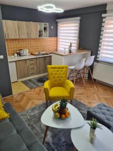 a living room with a yellow chair and a table at Town Square Apartment in Brčko