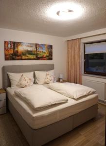 - une chambre dotée d'un grand lit avec des draps et des oreillers blancs dans l'établissement Haus Walser, à Tarrenz