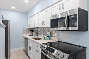 a kitchen with white cabinets and black appliances at Caloosa Cottage at Palm View Inn of Sanibel with Bikes in Sanibel