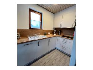 eine Küche mit weißen Schränken, einem Waschbecken und einem Fenster in der Unterkunft Haus im Schwarzwald in Lenzkirch